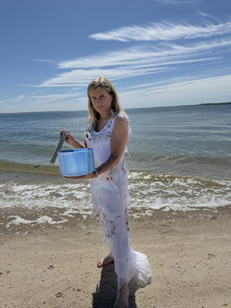 Sound Bath Practitioner Lisa Cooper Playing Singing Bowl on North Fork Beach